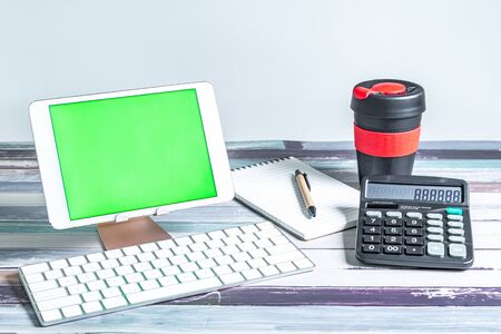Office and school stationery supplies, reusable cup, keyboard and mobile tablet with green screen. Business Objects Technology concept.の写真素材