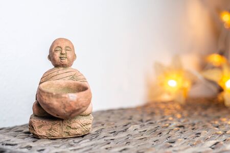 Miniature monk statue. Illuminated background. Home ornament decoration concept. Empty copy negative space for text.の写真素材
