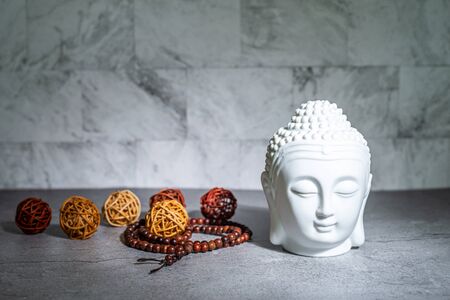 Home decoration ornament. White buddha head face, rattan cane balls. Marble texture wallpaper background concept.の写真素材