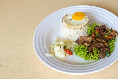 Chinese stir-fried spicy pepper beef with lettuce, jasmine white rice, pickled vegetables and sunny-side up fried eggの写真素材