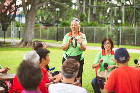 A group of seniors elderly retired active asian men women playing musical instrument singing happily enjoying life outdoorのeditorial素材