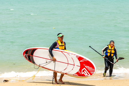 Men and women windsurfers carry boards after surfingのeditorial素材