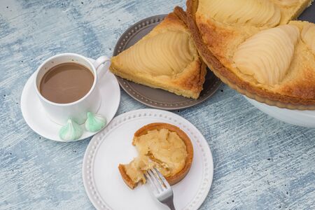 Delicious home bake poached pear tart pie, as known as Tarte Bourdaloue, a cup of coffee latte. It is a french popular recipe that gets the name from a street in Paris. Breakfast, brunch, afternoon food on table concept.の写真素材