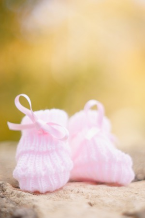 white Baby booties on a green natural background in autumnの写真素材