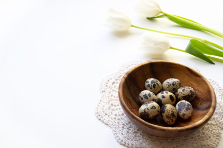 Easter composition. Easter eggs in a wooden plate in the sunlight with tulips on a white background