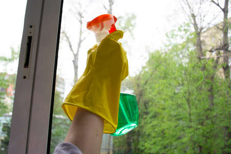 Hands with a window cleaning cloth. Washing the glass on the windows with a spray gun. Cleaning plastic windowsの写真素材