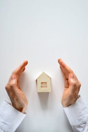 White house model and protecting female hands on a white background. Vertical footage
