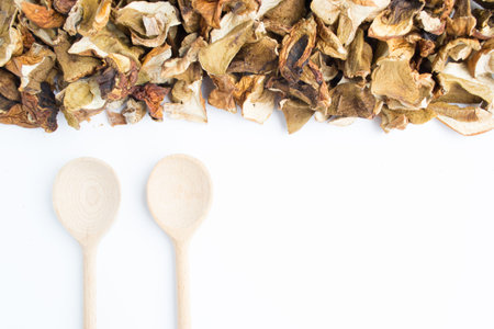 Dried porcini mushrooms on a white plate with wooden spoons. Ingredients for mushroom soup