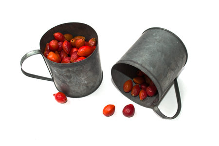 Fresh berries of wild rose in a metal mugs on a white background. Vitamin C in rosehipsの写真素材