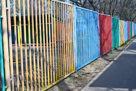 The colorful wooden fence of the kindergarten along the road. Slatted fence