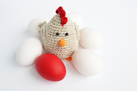 Crocheted hen with white and red Easter eggs on a white background. Crochet toys. easter cardの写真素材