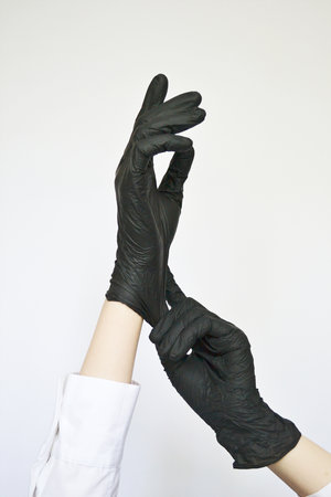 Woman hands put on black rubber gloves for protection.の写真素材