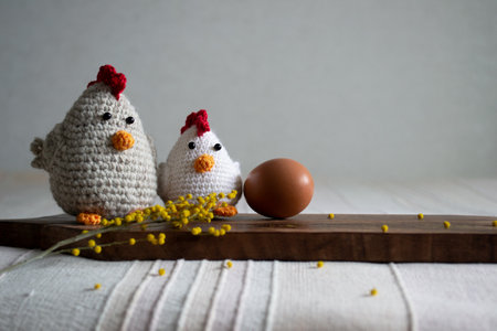 Easter Crocheted chicken and hen with chicken egg and mimosa on light background.の写真素材