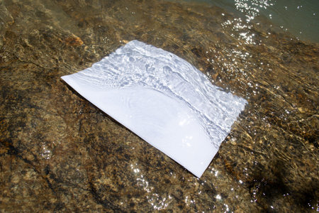 Mockup of sheet submerged under water, on the background of rocky bottom in the glare of the sun.