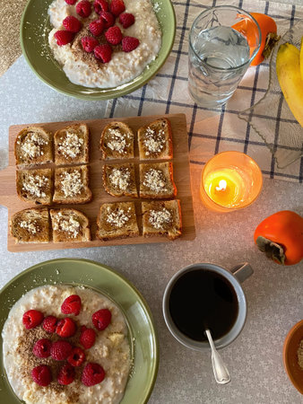 Flat lay breakfast with oatmeal porridge and raspberries, toast with honey and nuts on a wooden...