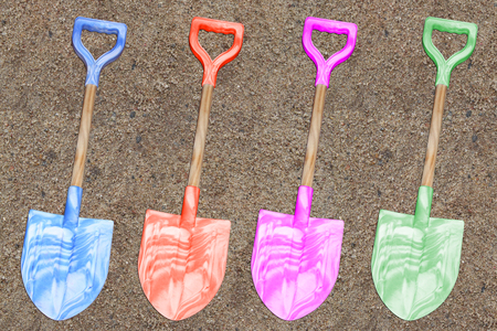 plastic toy shovels in a sand backgroundの写真素材