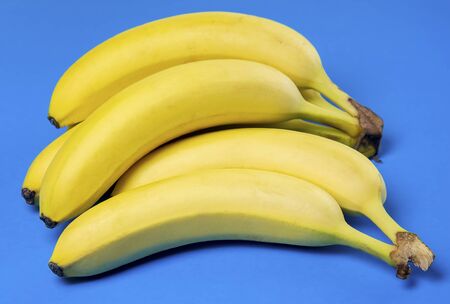 Bunch of ripe bananas on blue tabletopの写真素材