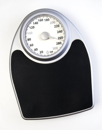 A traditional analog weight scale with a black surface and a white dial.の写真素材