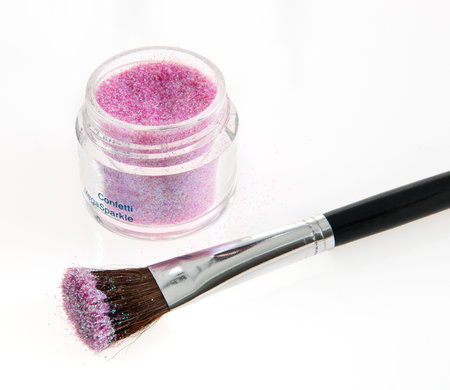 Purple glitter pigment and black-handled makeup brush showcased on a clean, white background, portraying elements of beauty, creativity, and cosmetic artistry.の写真素材