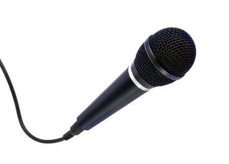 A close-up image of a black microphone with a cord, positioned against a plain white background. Ideal for illustrating concepts related to audio recording, music production, and public speaking.の写真素材