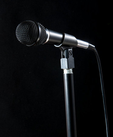 A high-quality microphone setup positioned against a dark, dramatic background, perfect for presentations, performances, and recording purposes. Ideal for illustrating audio, music, or voice scenarios.の写真素材