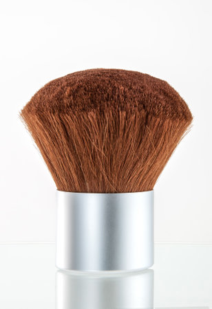 A professional-quality cosmetic powder brush designed with soft, dense bristles and a sleek silver handle. Perfect for even and smooth application of makeup powders, offering a comfortable grip and precise control.の写真素材