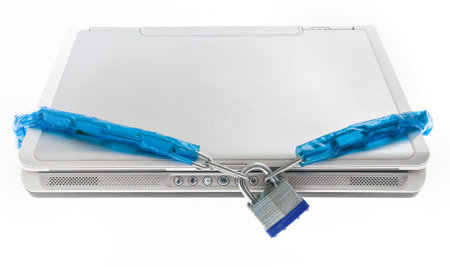 A laptop tightly secured with a blue-wrapped chain and a silver padlock highlights the concept of digital security and protection against threats. Useful for themes of cybersecurity, data protection, and online privacy.の写真素材