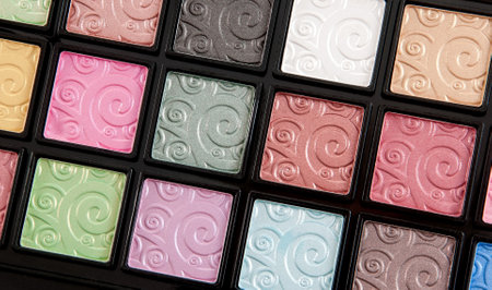 A closeup photograph showcasing vibrant eyeshadow palette squares, featuring an array of colors and intricate swirled embossing. Perfect for beauty, cosmetics, and makeup-focused themes showcasing creativity and precision.の写真素材