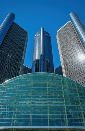 Glass-covered skyscrapers merge urban sophistication with modern architecture. Angular designs reflect blue skies, emphasizing the height of these interconnected towers. A contemporary glass dome structure complements the city skyline, showcasing innovation.の写真素材