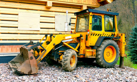 A yellow excavator built in front of a timbered building