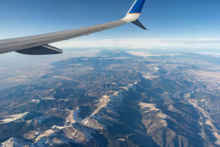 Looking out the window of an airplane soaring high above the scenic vista of the Rocky Mountains in the United States.の写真素材
