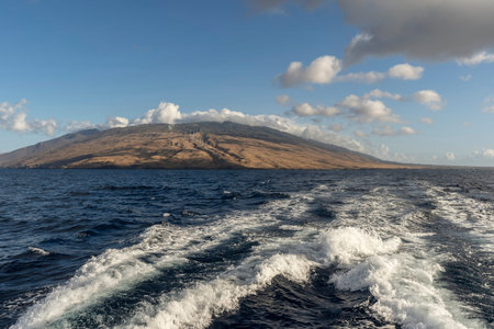 Sailing a catamaran across Maalaea Bay and looking back towards Wailuku and the island of Maui,...