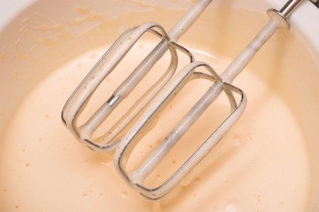 egg beater and a mixing bowl with beated eggs