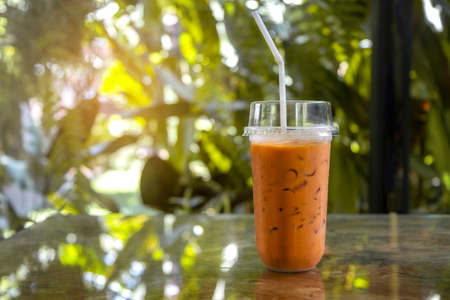Iced coffee  in plastic glass in bokeh warm light of summer and refresh on the wood  table in garden  nature background  in the morning or afternoon in coffee breakの写真素材