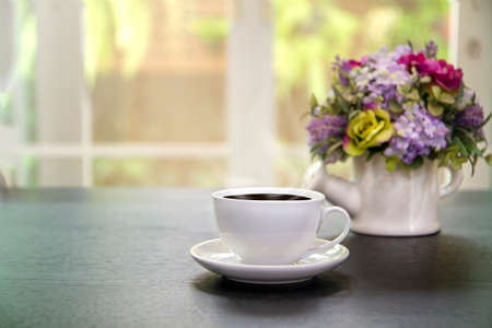Cups of coffee and vase with beautiful flower bouquet  on table in coffee shop background. Space for textの写真素材