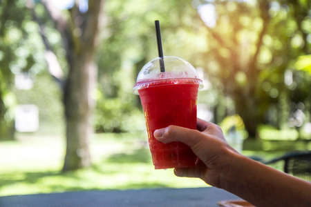 Hand holding a cup of fresh watermelon juice with summer on nature backgroundの写真素材