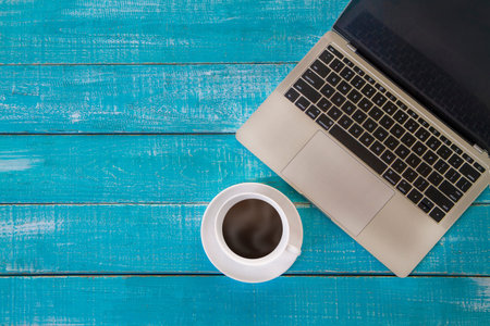 Top view of coffee cup and  laptop computer on green wooden background with copy space