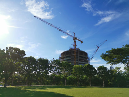 Construction of a high-rise building with cranes in the park