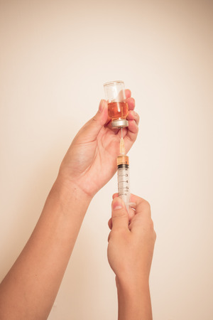 Syringe with vial on hands of a nurse,doctor administer the injection   (vignette)の写真素材