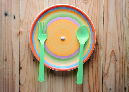 white pill on colorful dish, soft vintage tone   (concept for overeating medicine )