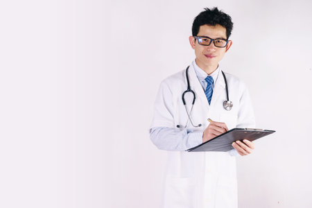 male doctor with clipboard and stethoscope writing prescriptionの写真素材