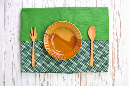 Wooden cutlery and disk on tablecloth over wooden tableの写真素材