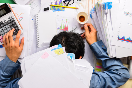 Businessman heavy workload sleep at office desk with finance sheet calculator and coffee.(concept for overworked)