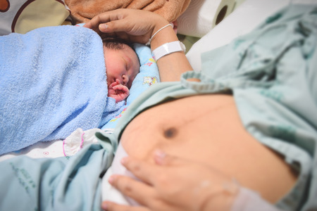 Newborn and Mother in hospital after giving birth (focused on newborn)の写真素材