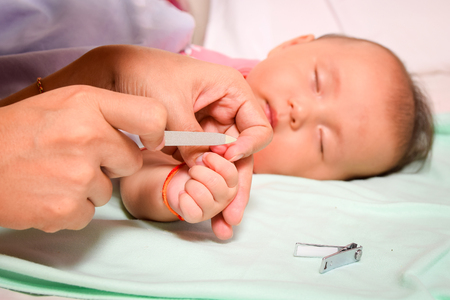 Mother manicure her child while the baby is sleeping.の写真素材