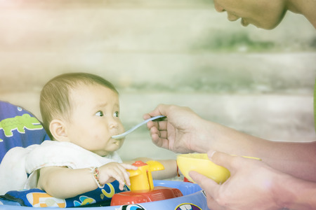 Father cheer helping baby eat  First solid food,rice of infants ,First Food for Baby after feeding (soft focus tone)の写真素材