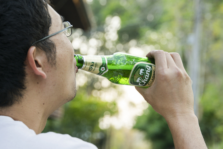 BANGKOK, THAILAND -February ,14  2016:Man drinking The New Chang Beer Bottle after work  in bangkon on February 14,2016.のeditorial素材
