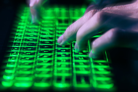 hands typing on keyboard in green light with motion blur,Concept for cybercrime hack cloud securityの写真素材