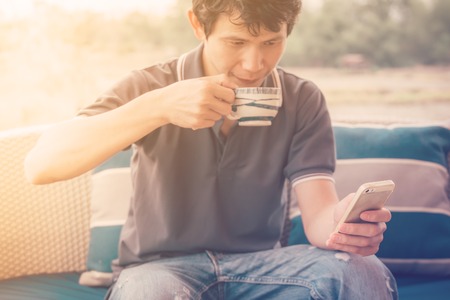 Man drinking coffee while using mobile phone ,selected focus and retro warm toneの写真素材