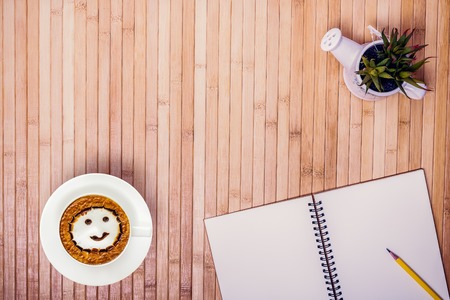Top view of  wooden desk with blank  white notebooks , coffee cup late art  smile shape milk foam and pencil with copy spaceの写真素材